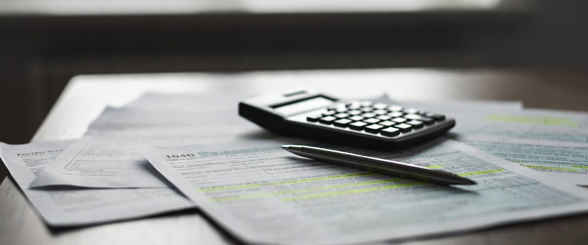 Desk with tax forms, calculator, and highlighted law amendments under review.