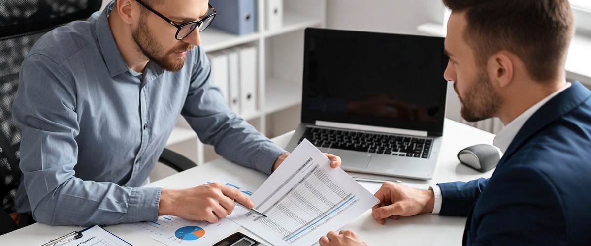 Accountant and client discussing entity change with financial reports and compliance checklist.