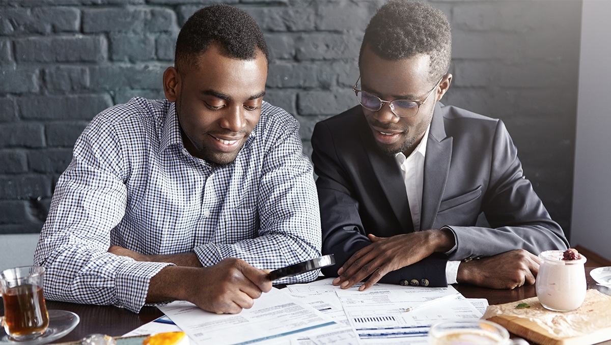 Business owner reviewing financial reports with accountant in modern office meeting room.