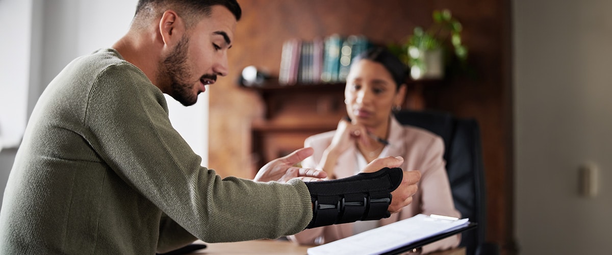 Person with arm in sling reviewing financial plan with advisor, symbolising income protection and disability insurance.